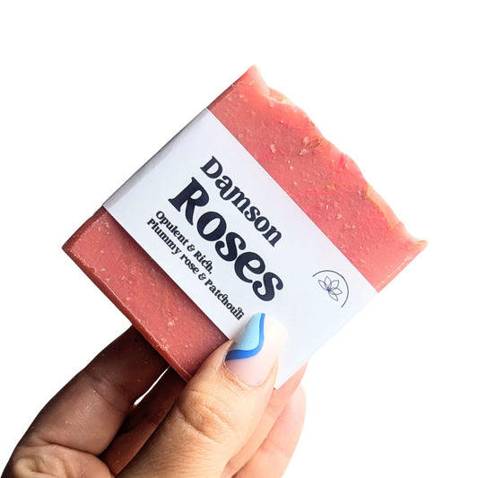 Holding a bar of rose soap against a white background