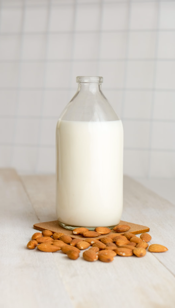 Photo of a bottle of milk and some almonds. Photo taken by Sandi Benedicta Represents the Almond Joy Soy wax melt fragrance.