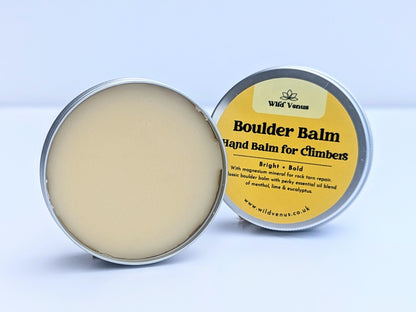A open tin of Boulder Balm Hand Balm for Climbers. The product is on its side with the lid tucked behind the open tin. The product is against a white label. 