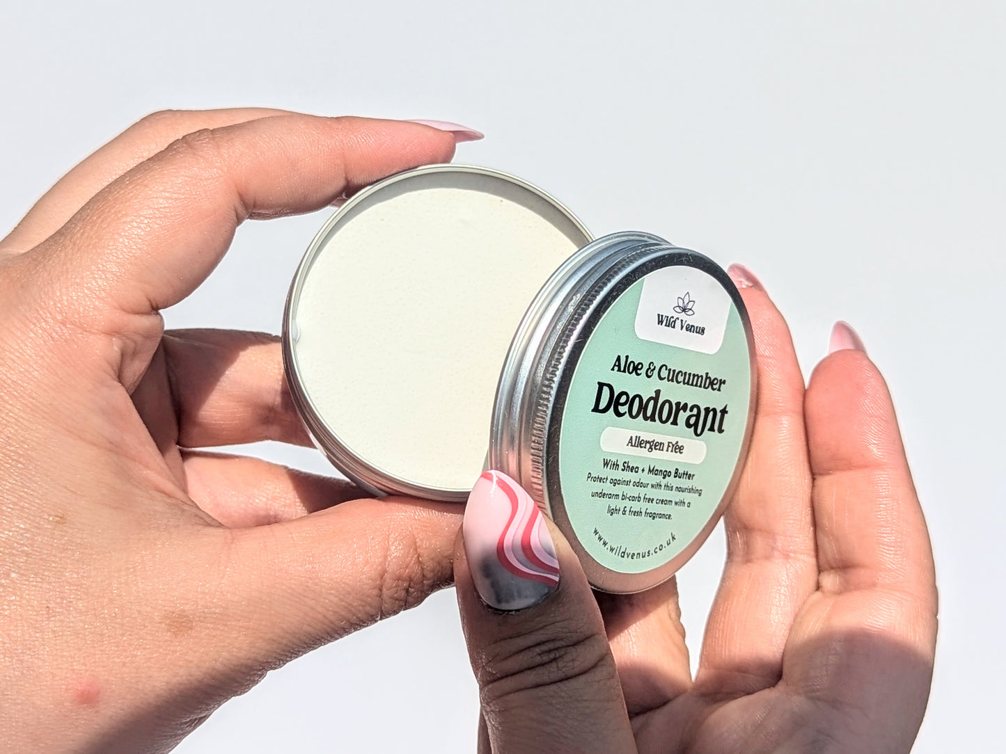 A pair of hands are opening a tin of aloe and cucumber scented allergen free deodorant. 