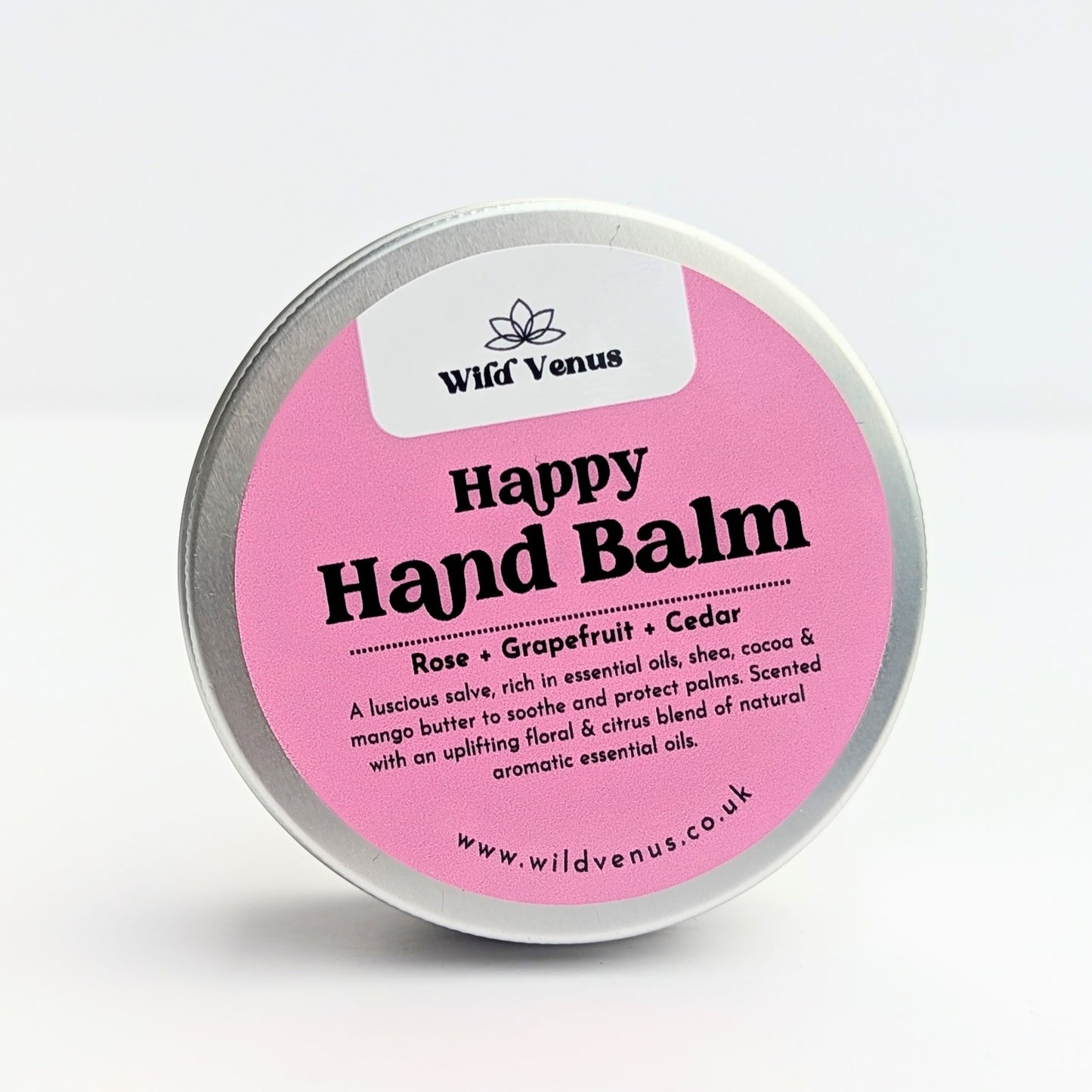 A tin of Happy Hand Balm against a white background. The label is pink and white with black writing.