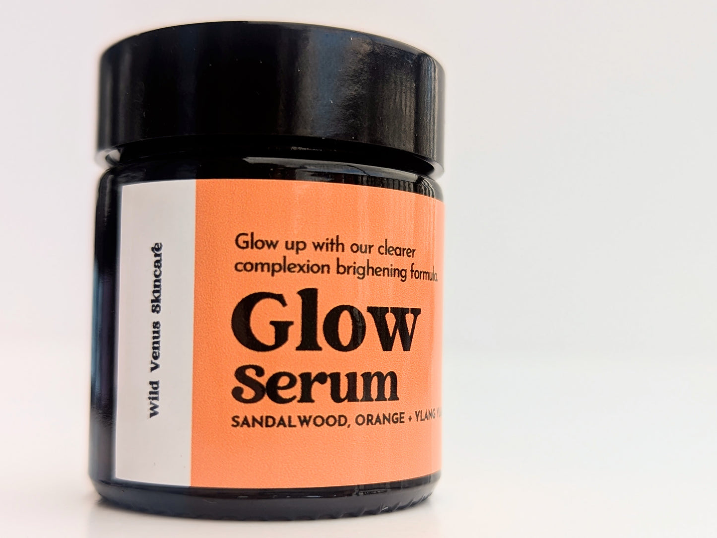 A close up of the pot of Glow serum. The product is shot against a white background and shows the side of the label. 