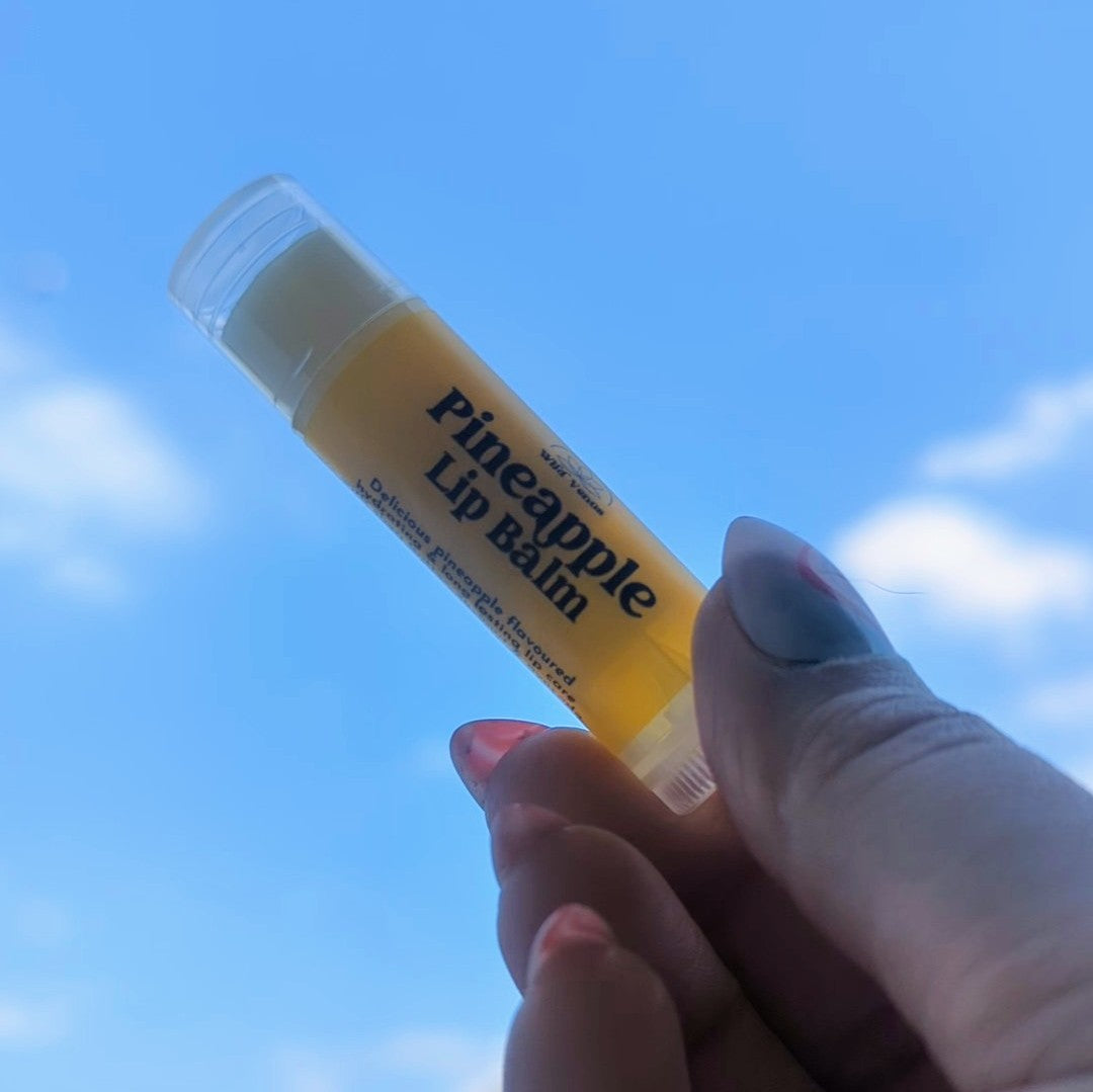 Holding a pineapple lip balm up to the sky.