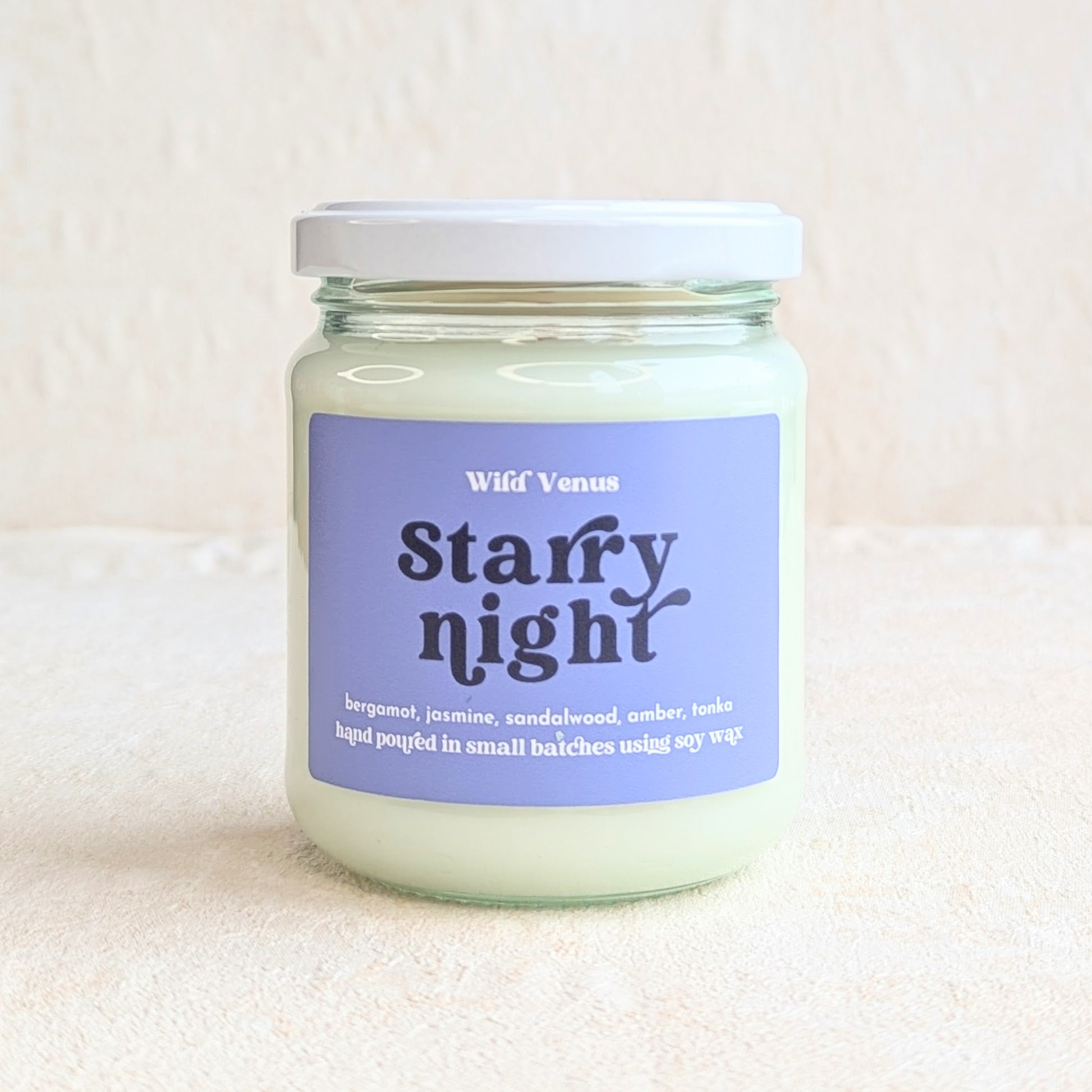 The starry night soy candle is on a white surface and against a white background. It is shown with its lid on.