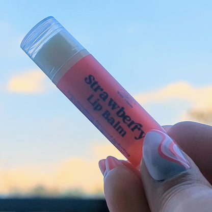 Holding a strawberry lip balm up to the sky.