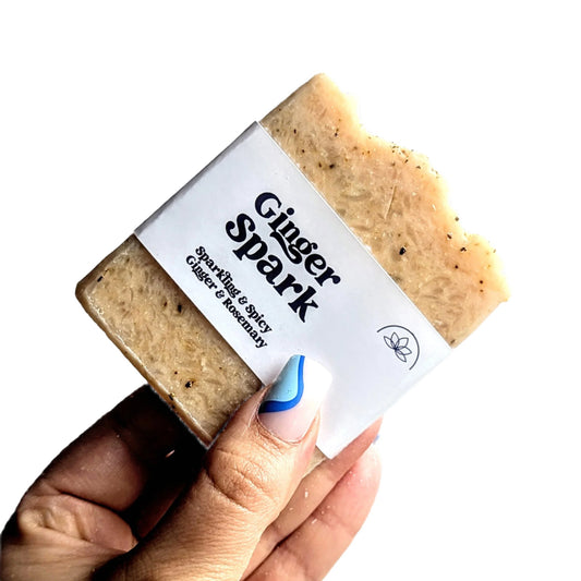 Holding a bar of ginger and rosemary soap against a white background.