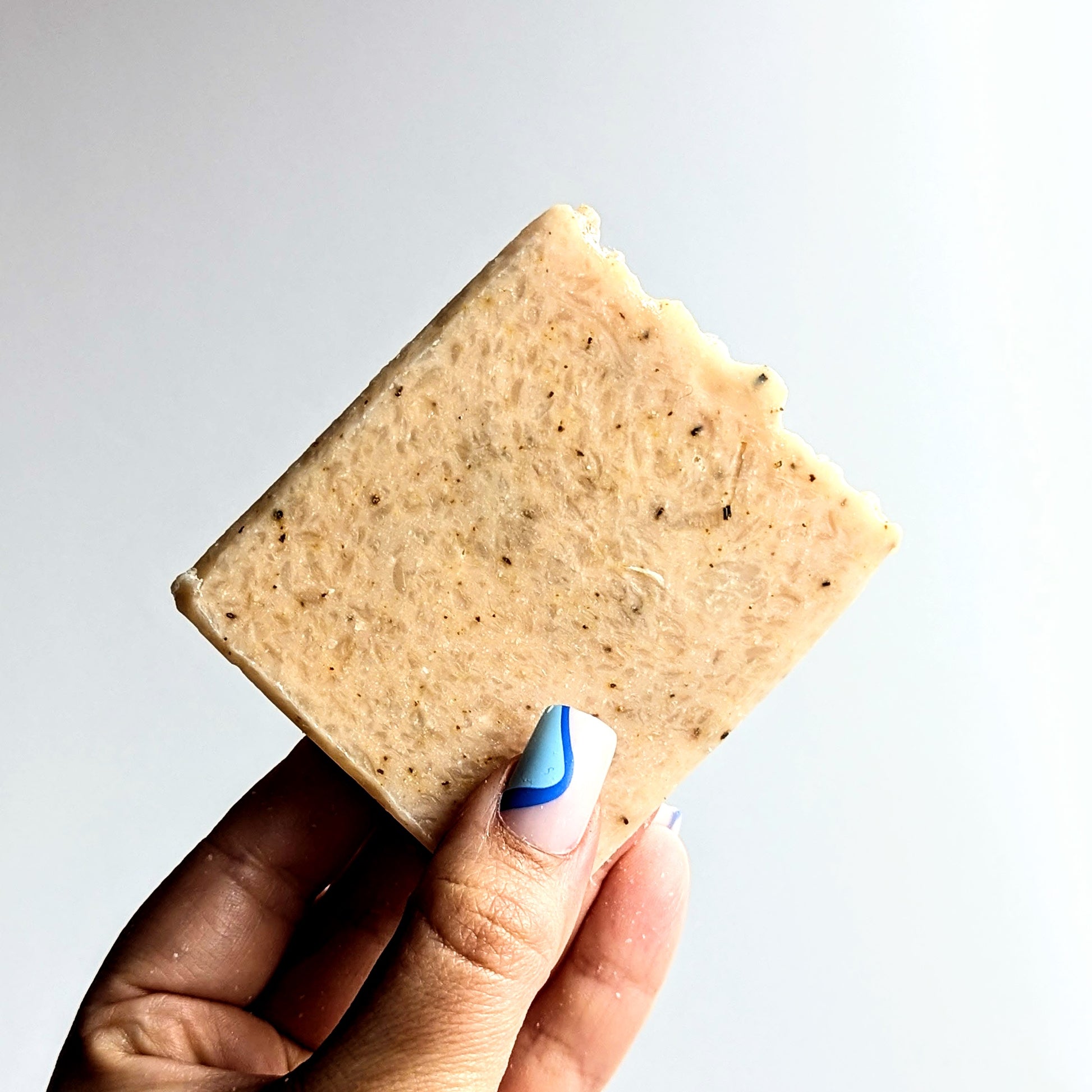 holding a naked bar of ginger and rosemary soap.