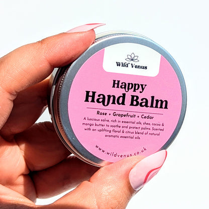 Holding a tin of the rose happy hand balm. 