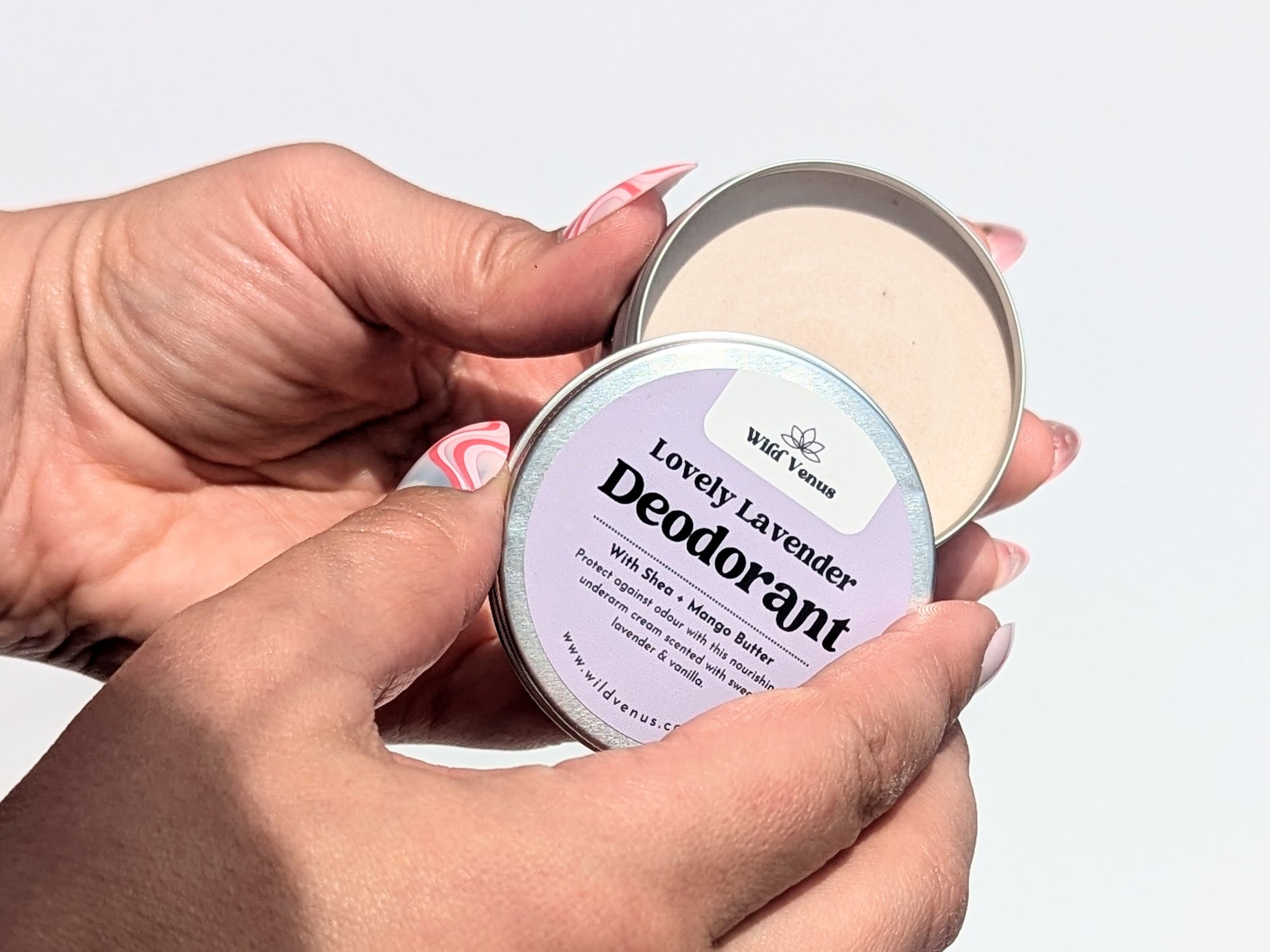 Opening a Lovely Lavender deodorant in the sun with both hands. 